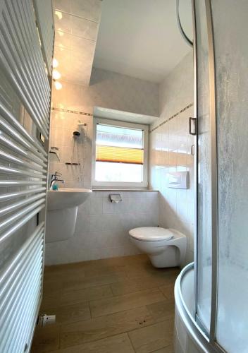 a bathroom with a toilet and a sink and a window at Süderhaus Hiddensee App 7 in Neuendorf