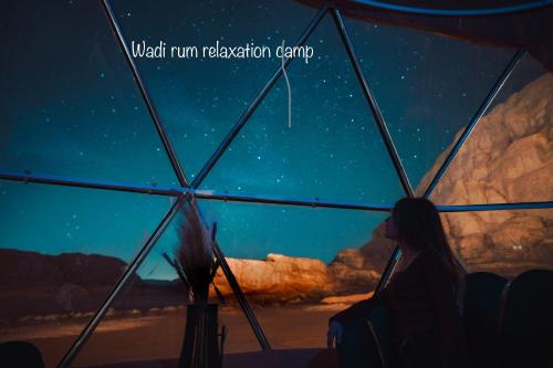 a woman sitting under a tent looking at the stars at Wadi Rum Relaxation Camp in Wadi Rum