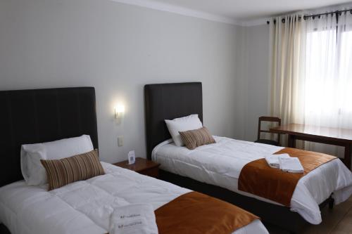 um quarto de hotel com duas camas e uma secretária em Hotel Qhawarina de Casas Kolping Bolivia S.R.L. em Sucre