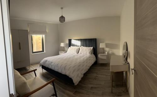 a white bedroom with a bed and a desk and a bed sidx sidx sidx sidx at Seabreeze Cottage in Portstewart