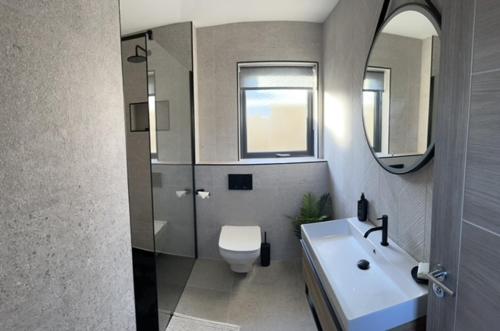 a bathroom with a sink and a toilet and a mirror at Seabreeze Cottage in Portstewart