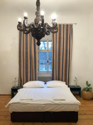 a bedroom with a bed with a chandelier and a window at Zámeček Ostrov in Ostrov