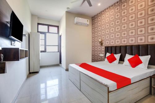 a bedroom with a bed with red pillows and a television at Super OYO Hotel Sky Orchid in Ludhiana