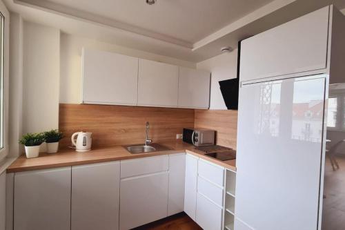 a kitchen with white cabinets and a sink at Słoneczny apartament w centrum Gdyni in Gdynia