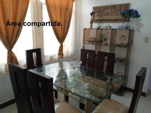 comedor con mesa de cristal y sillas en Acuarela del Rio H#3 Cerca Aeropuerto y Terminal Habitación privada con baño, en Guayaquil