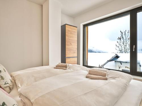 two beds in a room with a large window at The Mountain Hideaway 211 by AA Holiday Homes SKI IN SKI Out Die Tauplitz in Tauplitz