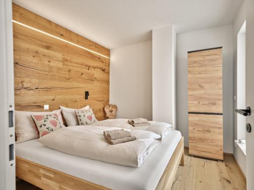 a bedroom with a large white bed with a wooden headboard at The Mountain Hideaway 211 by AA Holiday Homes SKI IN SKI Out Die Tauplitz in Tauplitz
