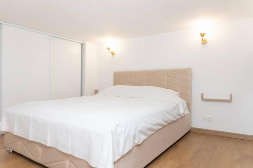 a white bedroom with a large bed with white sheets at Appartement T2 - Roubaix Centre in Roubaix