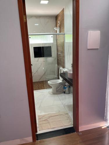 uma casa de banho com um WC e uma porta de duche em vidro. em Skyloft Chalé em Governador Valadares