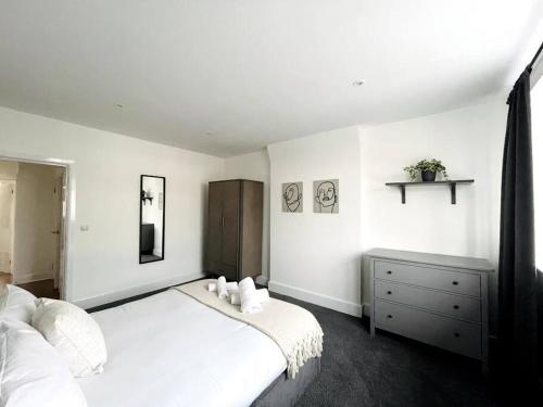 a white bedroom with a bed and a dresser at Solace in Bournemouth