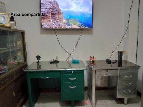 Habitación con escritorio y TV en la pared. en Acuarela del Rio H#3 Cerca Aeropuerto y Terminal Habitación privada con baño, en Guayaquil