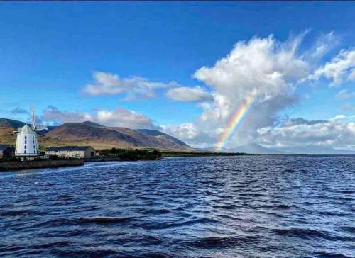 a rainbow over a body of water with a lighthouse at Atlantic Sea View in Tralee