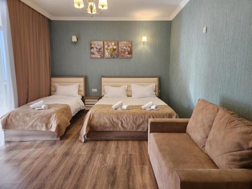 um quarto de hotel com duas camas e um sofá em Snow King Hotel em Bakuriani