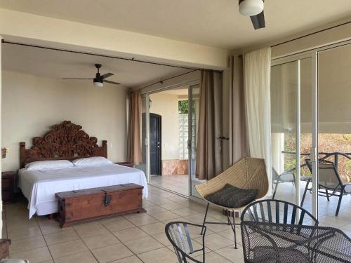 een slaapkamer met een bed en een balkon met stoelen bij Alojamientos Alexa in Sayulita