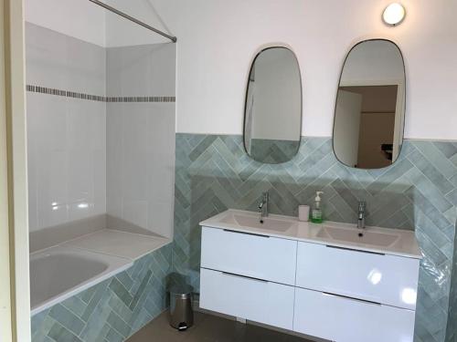 - une salle de bains blanche avec deux lavabos et une douche dans l'établissement La demeure des Rois - Parking - Metro - Stade de France, à Saint-Denis