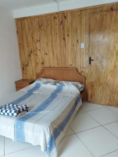 Bett in einem Zimmer mit einer Holzwand in der Unterkunft Barra do chui Brasil in Santa Vitória do Palmar