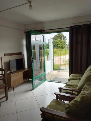 ein Wohnzimmer mit einem TV und einer Glasschiebetür in der Unterkunft Barra do chui Brasil in Santa Vitória do Palmar