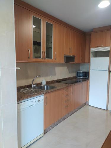 a kitchen with wooden cabinets and a white refrigerator at Piso Beiramar in Pontevedra