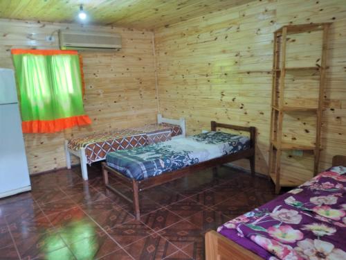 um quarto com duas camas num chalé de madeira em Cabaña Guaimbe em Eldorado