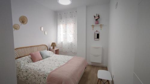 a white bedroom with a bed with pink pillows at Apartamento Flor de Córdoba in Córdoba