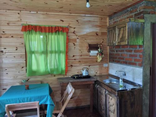 a kitchen with a table and a green window at Cabaña Guaimbe in Eldorado