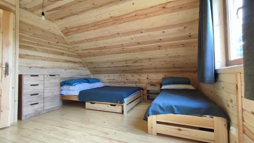 a bedroom with two beds in a wooden cabin at Winiec 218/8 in Miłomłyn