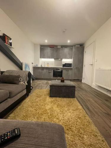 a living room with a couch and a kitchen at New London Apartment- 20mins from Central City in Romford