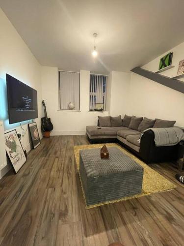 a living room with a couch and a tv at New London Apartment- 20mins from Central City in Romford