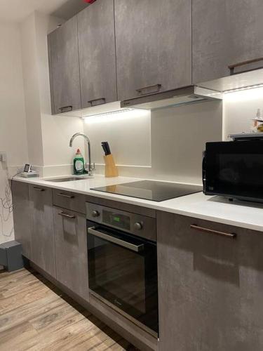 a kitchen with a sink and a stove top oven at New London Apartment- 20mins from Central City in Romford