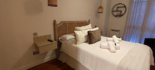 1 dormitorio con 1 cama con sábanas y almohadas blancas en Precioso piso con garaje en el centro de Castro Urdiales, en Castro Urdiales