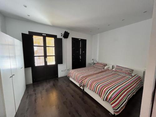 een slaapkamer met een bed met een gestreept dekbed en een raam bij Casa vacanze appartamento Ibiza città in Ibiza-stad