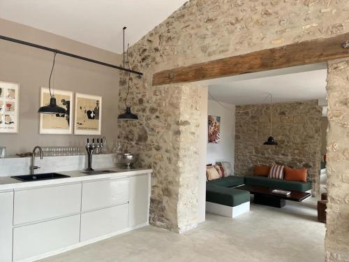 eine Küche und ein Wohnzimmer mit einer Steinmauer in der Unterkunft Gîte de charme Uzès de 10 à 24 personnes in La Bastide-dʼEngras