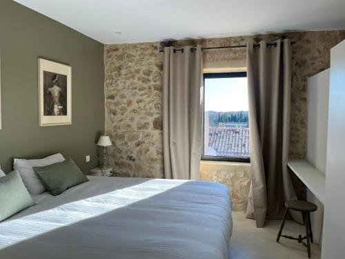 ein Schlafzimmer mit einem großen Bett und einem Fenster in der Unterkunft Gîte de charme Uzès de 10 à 24 personnes in La Bastide-dʼEngras