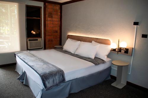 a bedroom with a bed with white sheets and a window at Soy Local San José in San José
