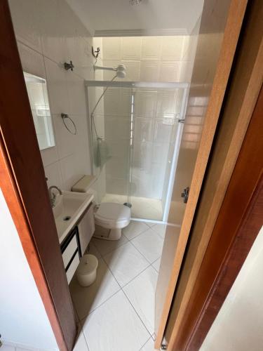 ein Badezimmer mit Dusche, Toilette und Waschbecken in der Unterkunft Casa aconchegante com ar condicionado para família em condomínio in Caraguatatuba
