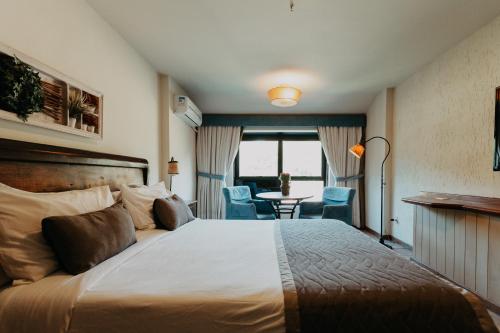 Kastel Itaipava في إتايبافا: غرفة فندقية بسرير وطاولة وكراسي