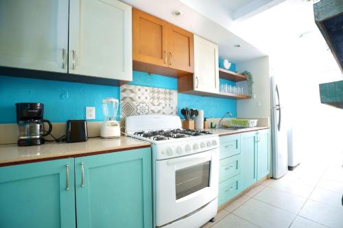 una cocina con armarios azules y un horno de fogón blanco en Casa de Colores en Playa del Carmen