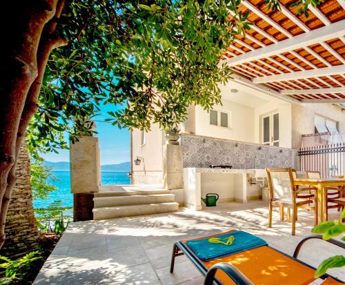 eine Terrasse mit einem Tisch, Stühlen und Meerblick in der Unterkunft Holiday Home Labineca in Gradac