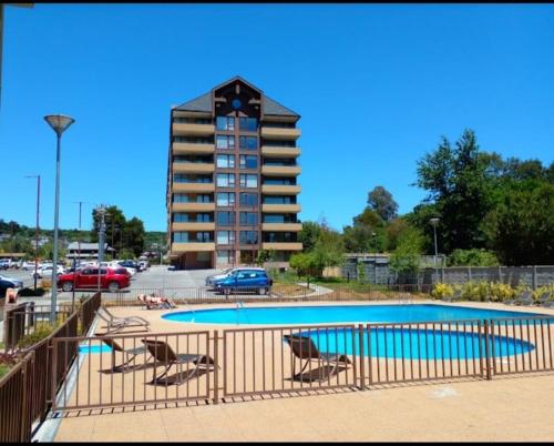 a swimming pool with two chairs and a building at Costanera Playa Villarrica in Villarrica