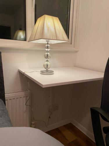 una lámpara sentada en un estante junto a una ventana en 1 Cozy Single Bedroom With Hot Drinks, en Reading