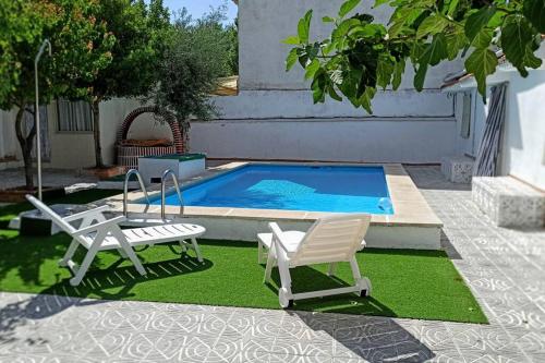 una piscina con 2 sillas de jardín y un par de sillas junto a una piscina en El Cortijo de Palma en Villarejo de Salvanés