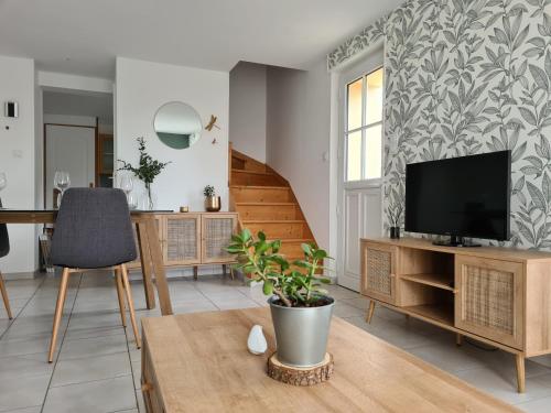 un salon avec une télévision et une table dans l'établissement Charmante Maison de 2 chambres, à Laroche-Saint-Cydroine