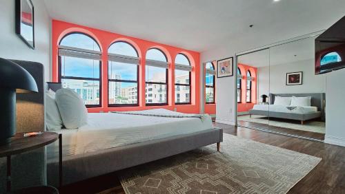 a bedroom with a large bed with red walls and windows at The Lofts on Clematis 503 Downtown West Palm Beach in West Palm Beach