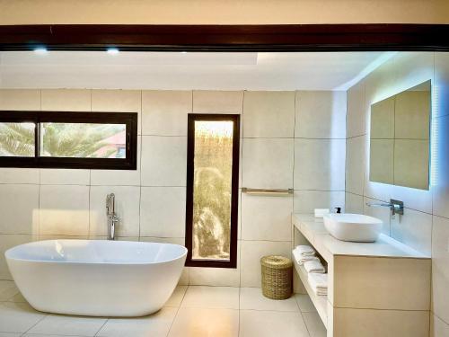 a bathroom with a large tub and two sinks at Le Kentia in Lomé