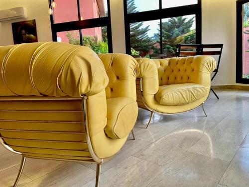 two yellow chairs in a room with windows at Le Kentia in Lomé