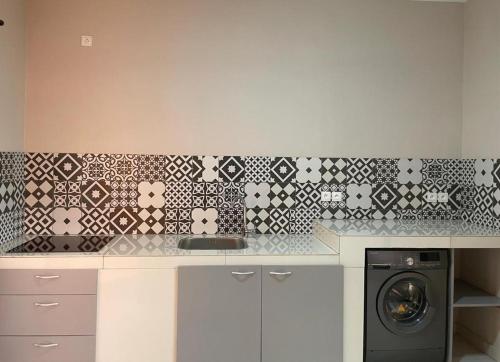 a kitchen with a washing machine and a tile wall at Le Kentia in Lomé