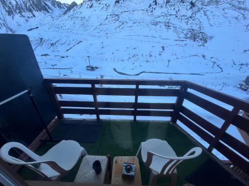 a balcony with two chairs and a view of a mountain at La Mongie 6 couchages pied de pistes in La Mongie