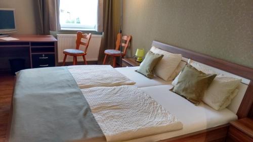 a bedroom with a large white bed with two chairs at Landgasthaus Oberbillig in Holsthum