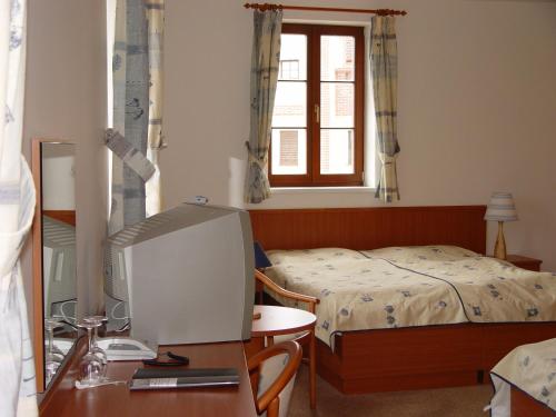 a bedroom with a bed and a computer monitor on a desk at Hotel Galerie in Třeboň