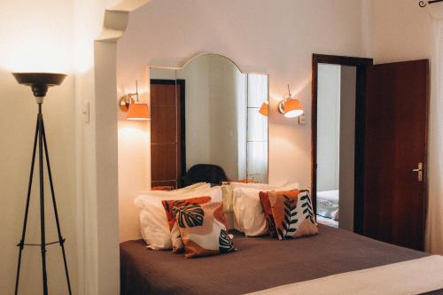 ein Schlafzimmer mit einem Spiegel und einem Bett mit Kissen in der Unterkunft Urca Hotel in Rio de Janeiro